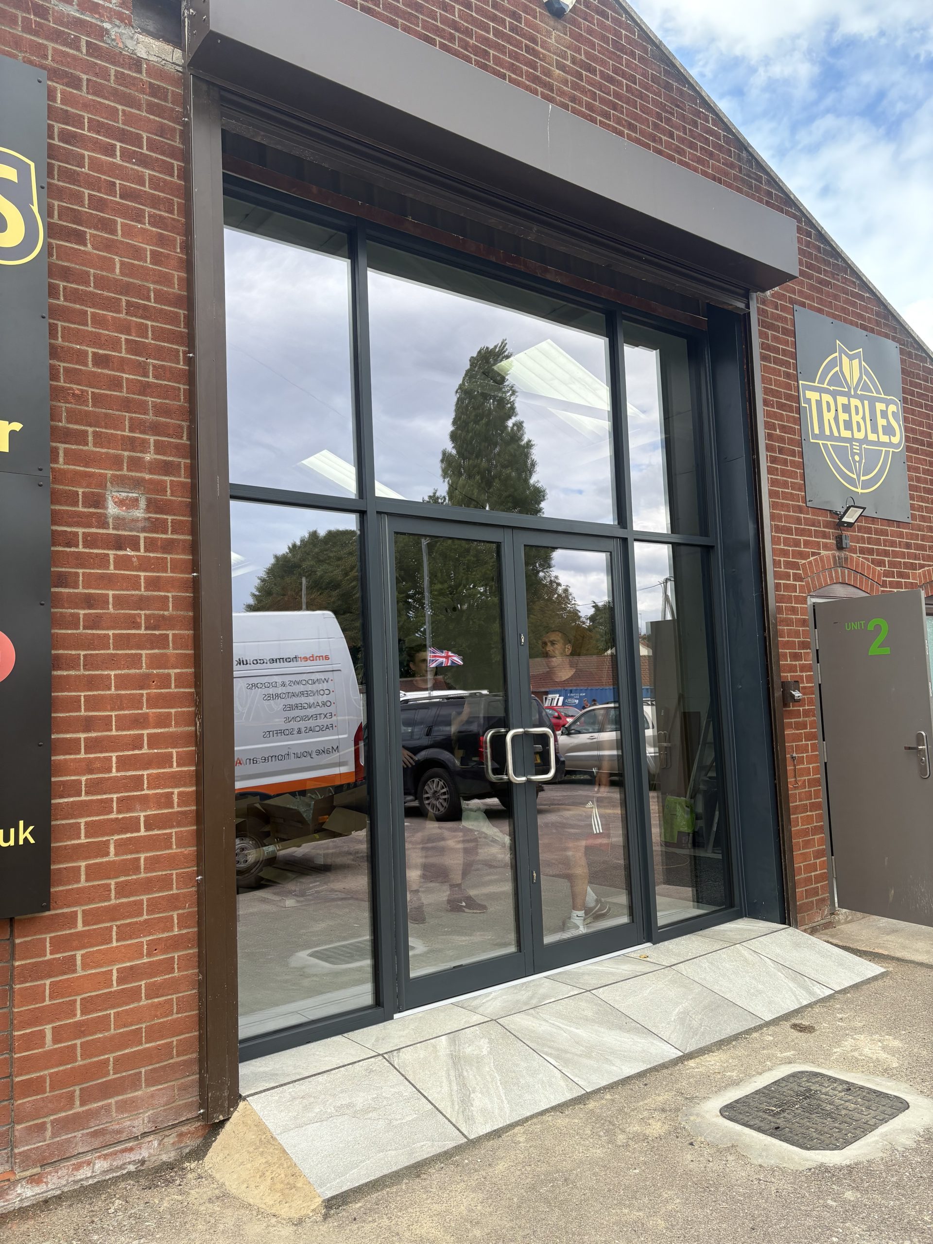 New aluminium shopfront with glazed double doors at Trebles Darts, North Walsham by Amber Home Improvements.